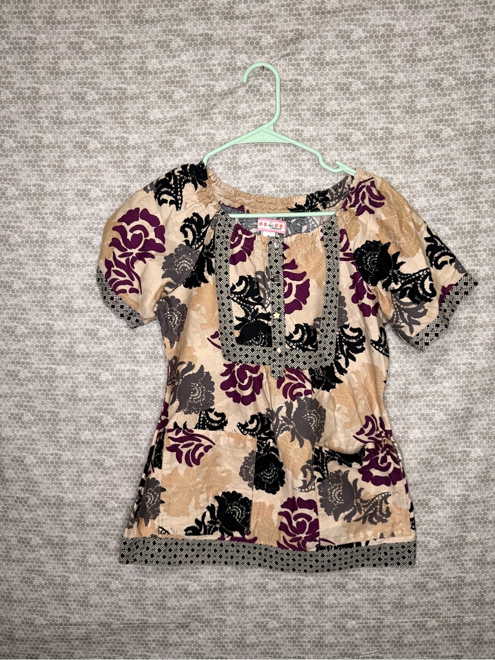 Small Scrub Top black and purple floral blouse with beige background